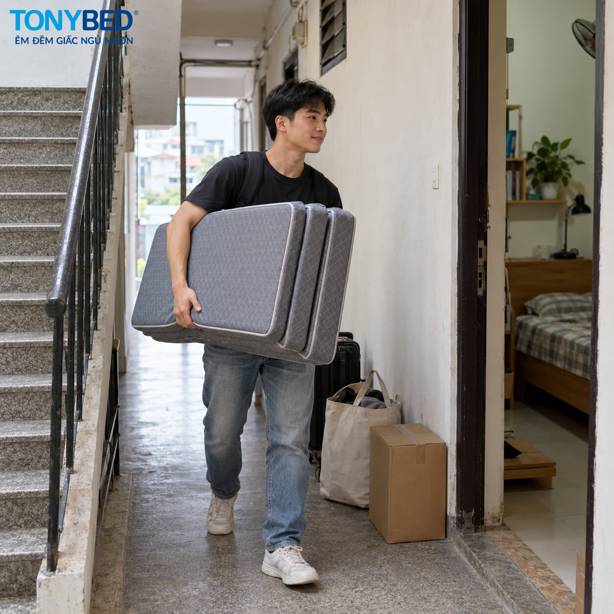 Người trẻ mang nệm gấp 3 qua hành lang khi chuyển phòng trọ